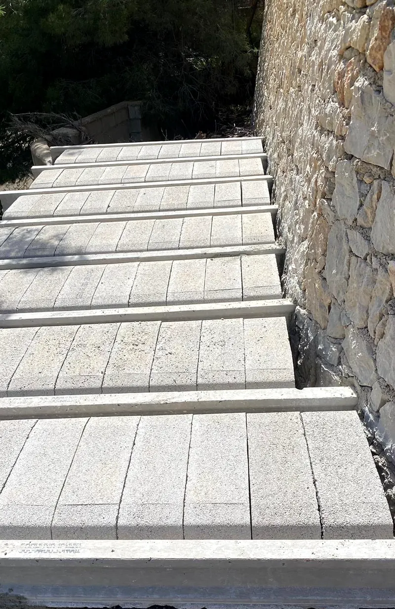 Concrete beams and blocks laid for a new floor beside a natural stone wall