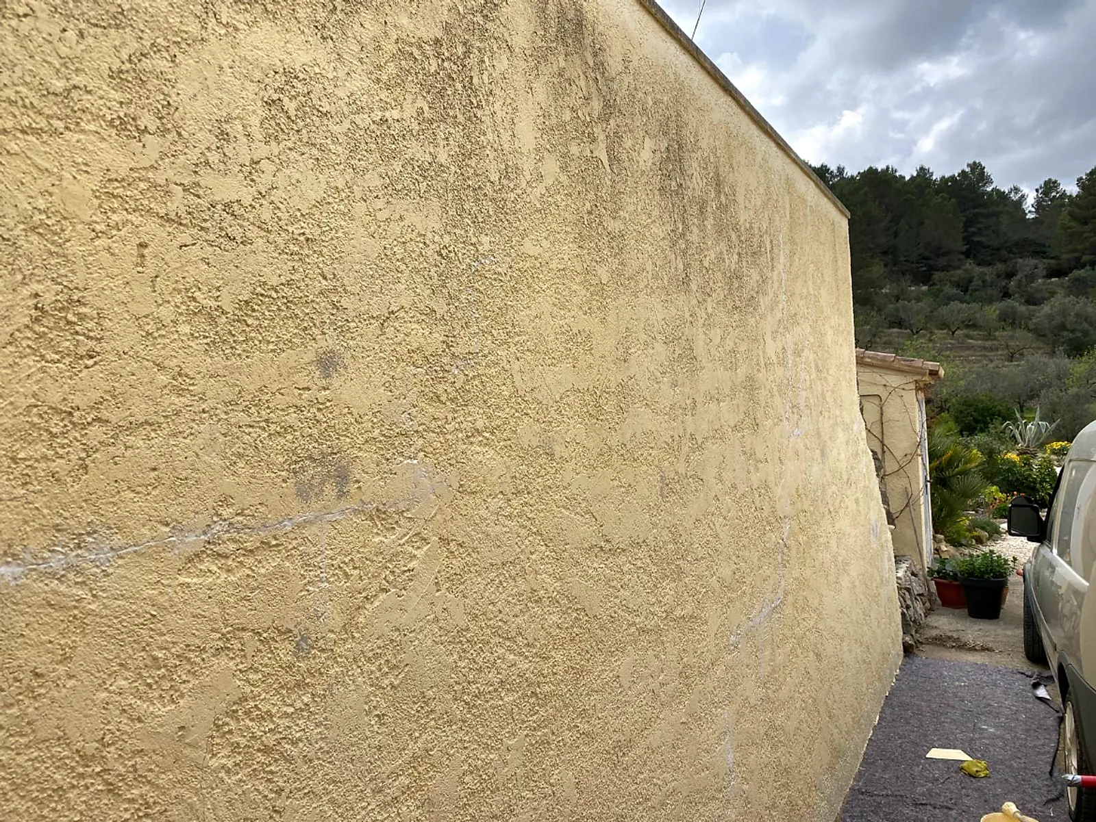 Before: long exterior wall with patchy, cracked render