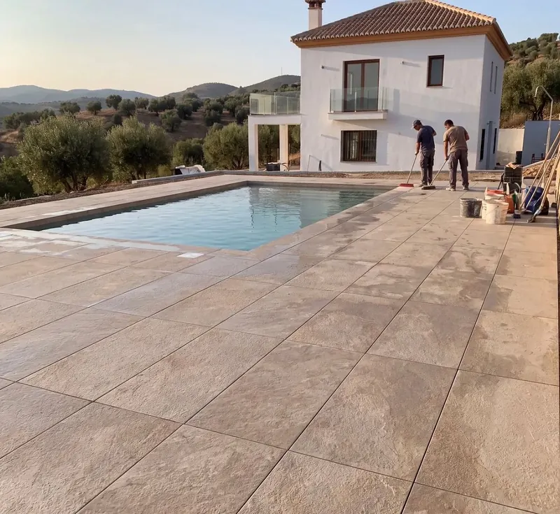 Pool terrace laid with large stone-effect porcelain tiles