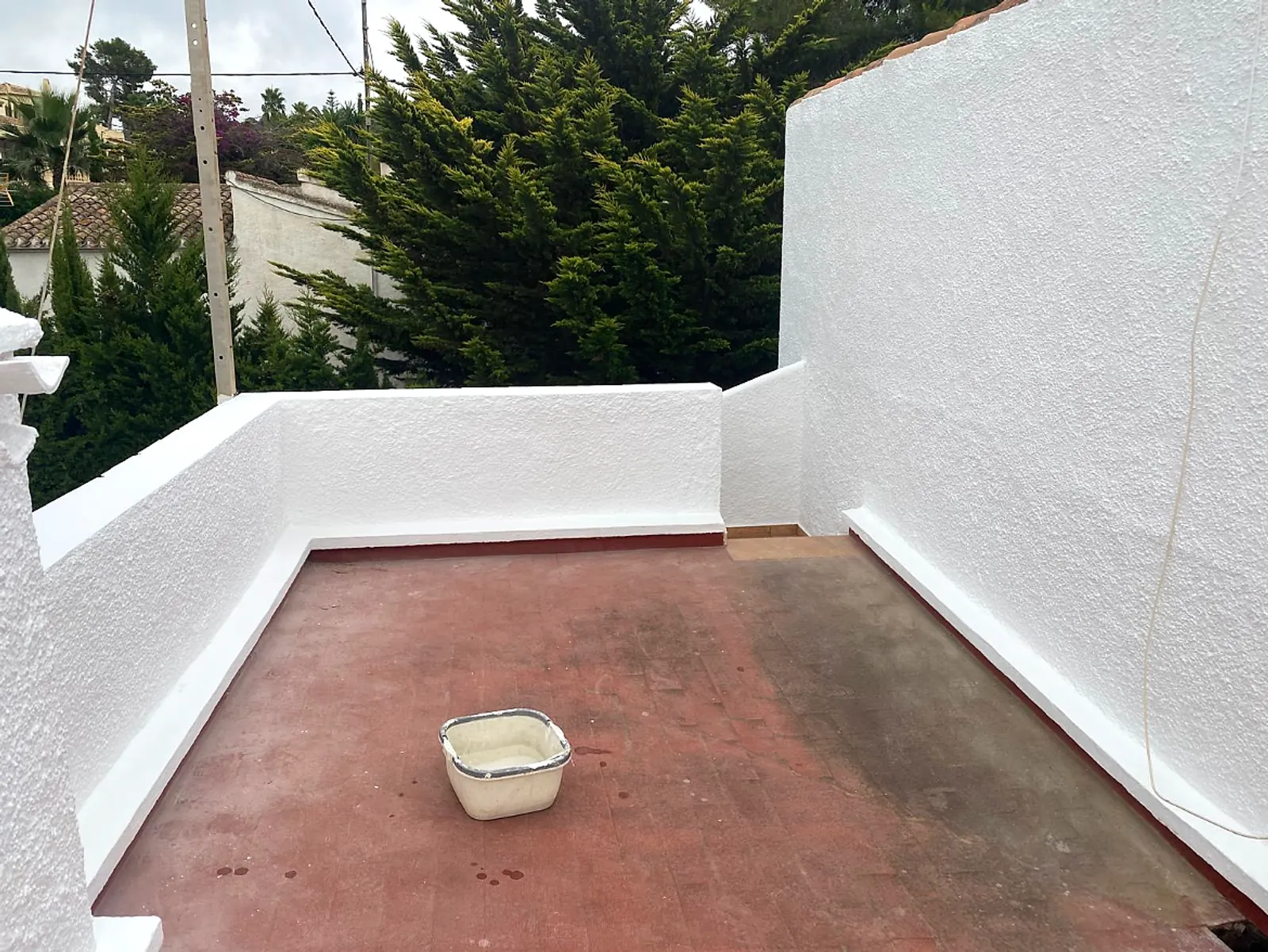After: the same terrace walls rendered and painted bright white