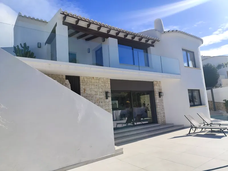 Modern white villa with glass balconies, timber pergola and stone cladding